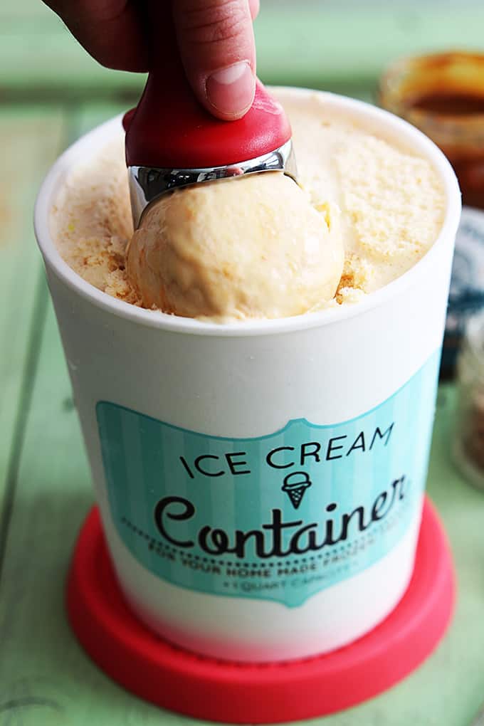 an ice cream scooper scooping out some butterscotch ice cream from a container.