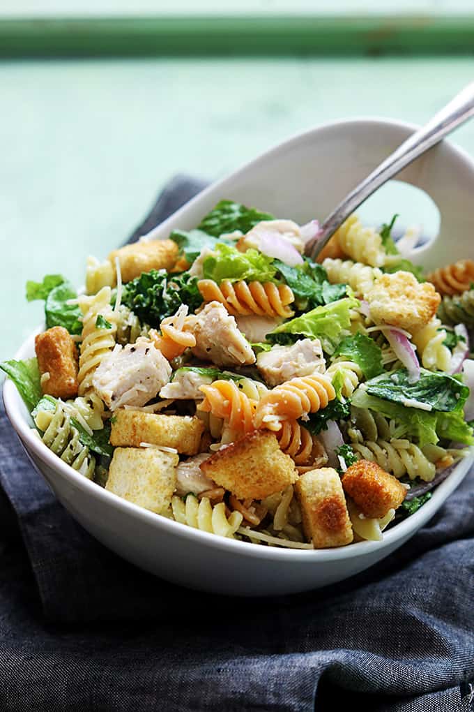 chicken caesar pasta salad in a bowl with a spoon.