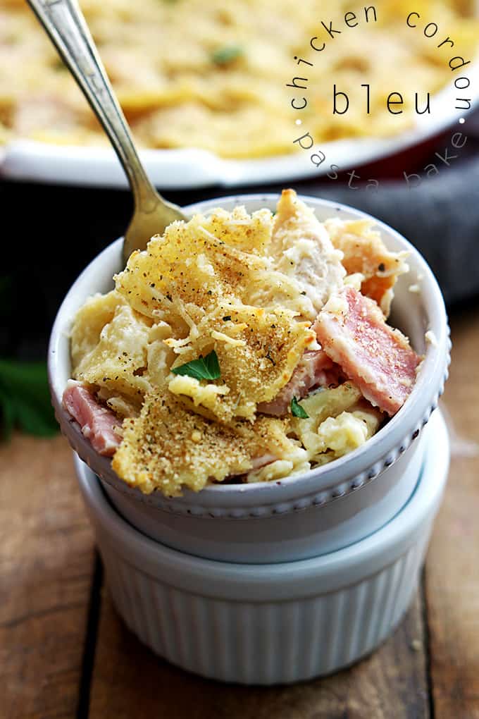 chicken cordon bleu pasta bake in a small bowl stacked on another bowl with a fork and the title of the recipe written on the top right corner of the image.