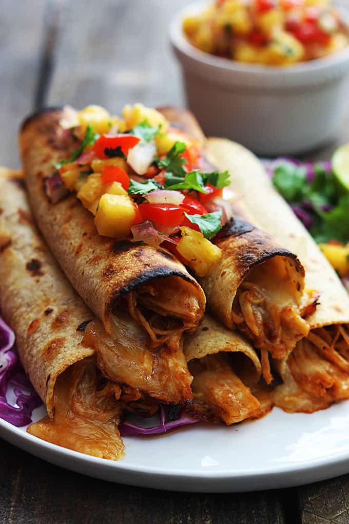 slow cooker Hawaiian bbq chicken taquitos topped with pineapple salsa on a plate.