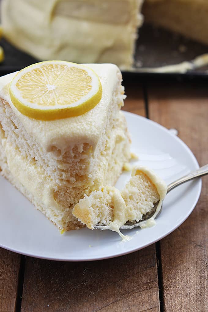 a piece of one bowl lemon cake on a plate with a fork with a bite on it on the side.