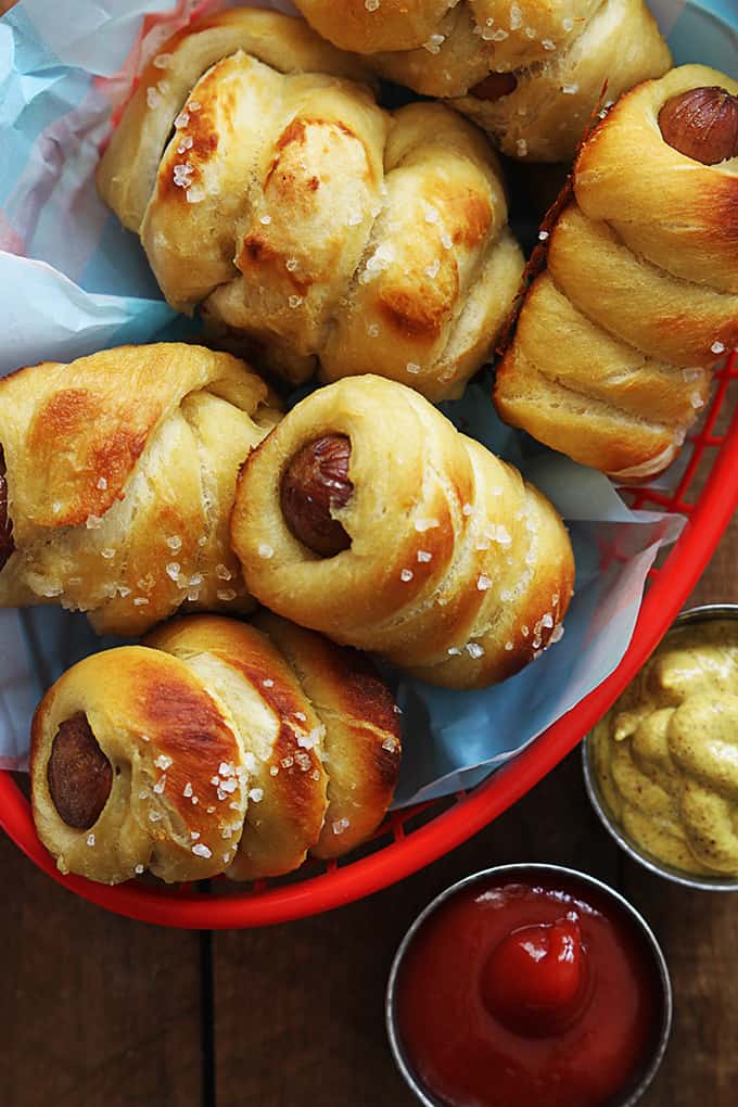 top view of pretzel dogs in a basket with ketchup and mustard on the side.