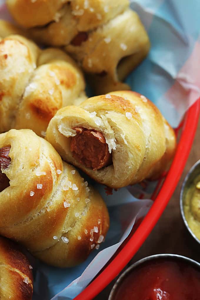 top view of pretzel dogs in a basket with ketchup and mustard on the side.