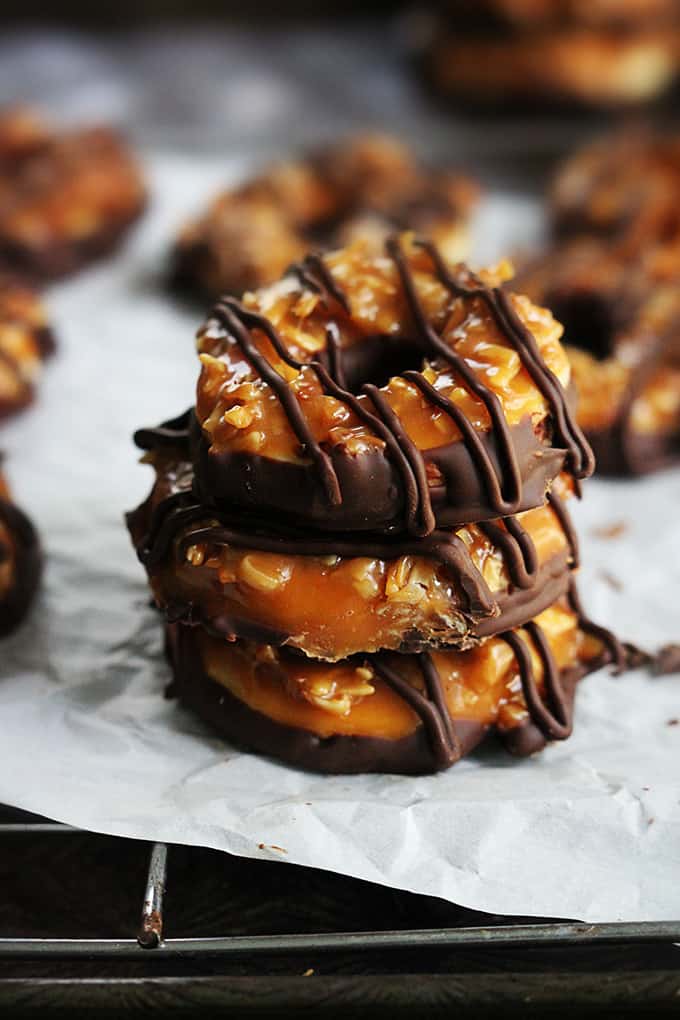 stacked homemade Samoas on a cooling rack with more cookies faded in the background.
