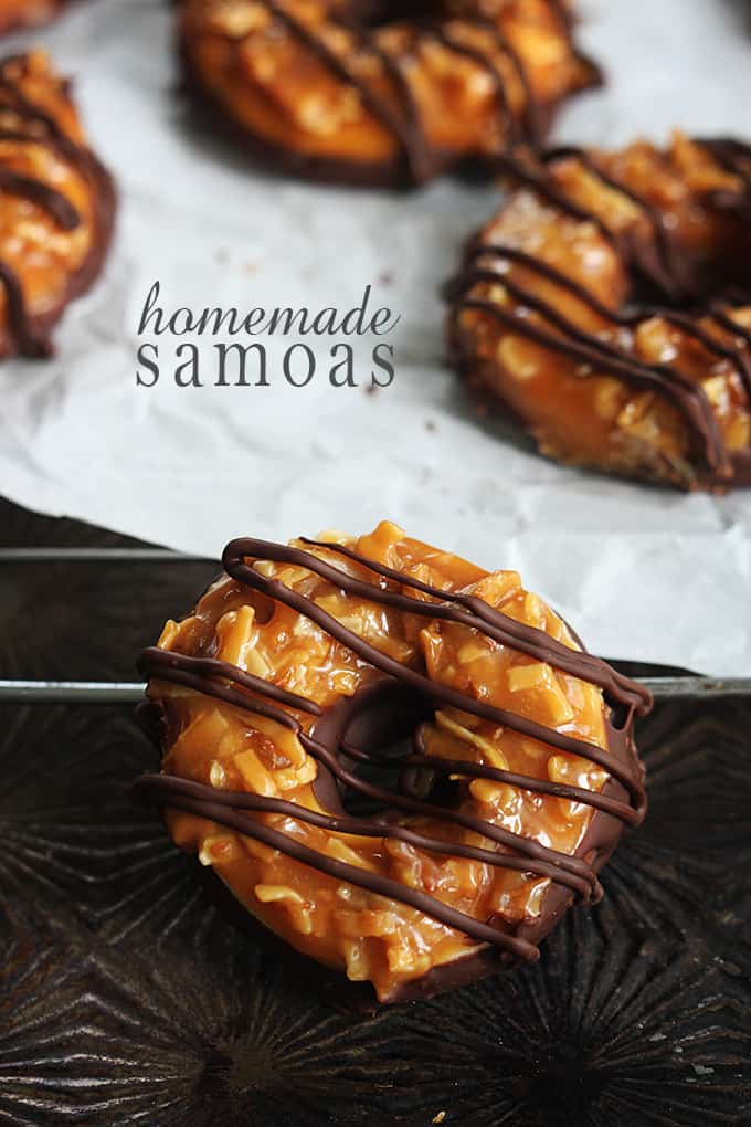 a homemade Samoa cookies with more cookies in the background with the title of the recipe written in the middle left of the image.
