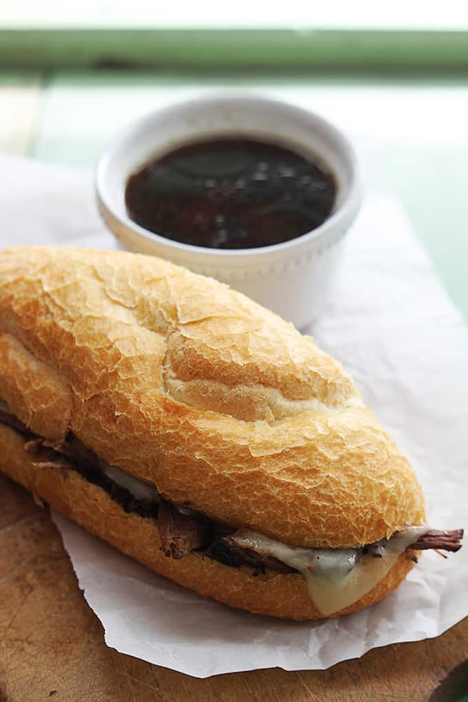 a slow cooker French dip sandwich next to a bowl of French dip.