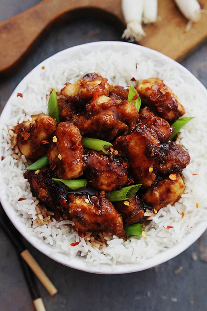 top view of general tso's chicken on rice in a bowl with chopsticks on the side.