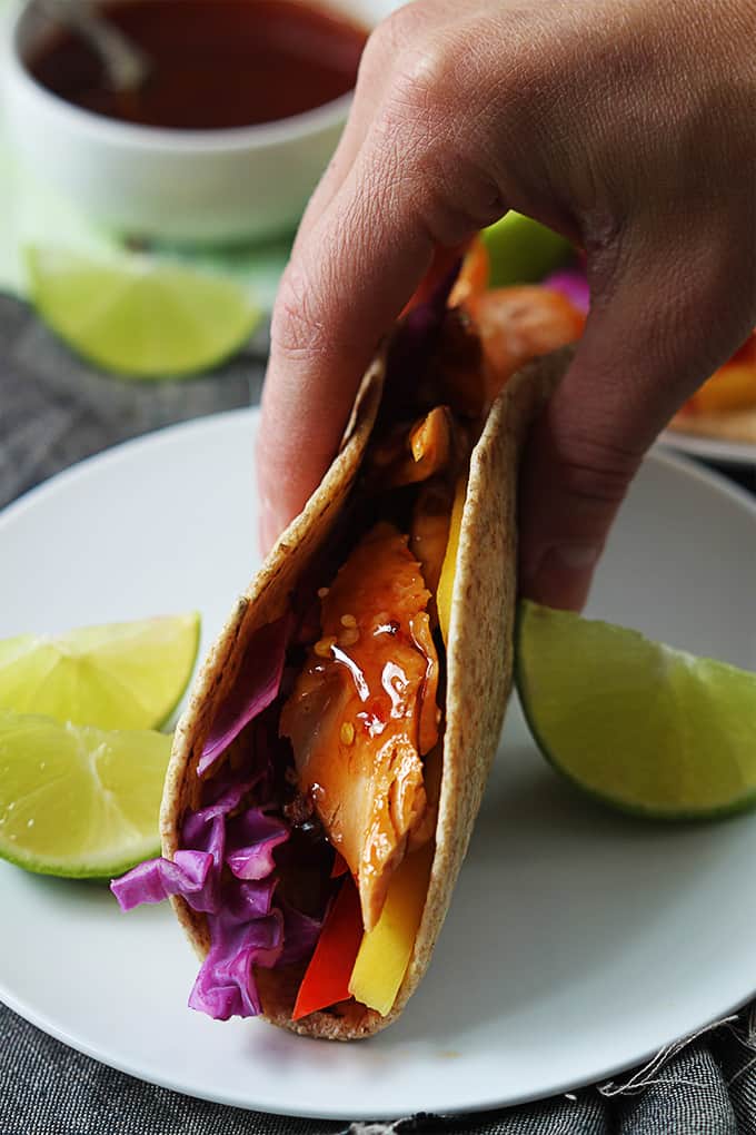 a hand picking up a Thai salmon taco from a plate.