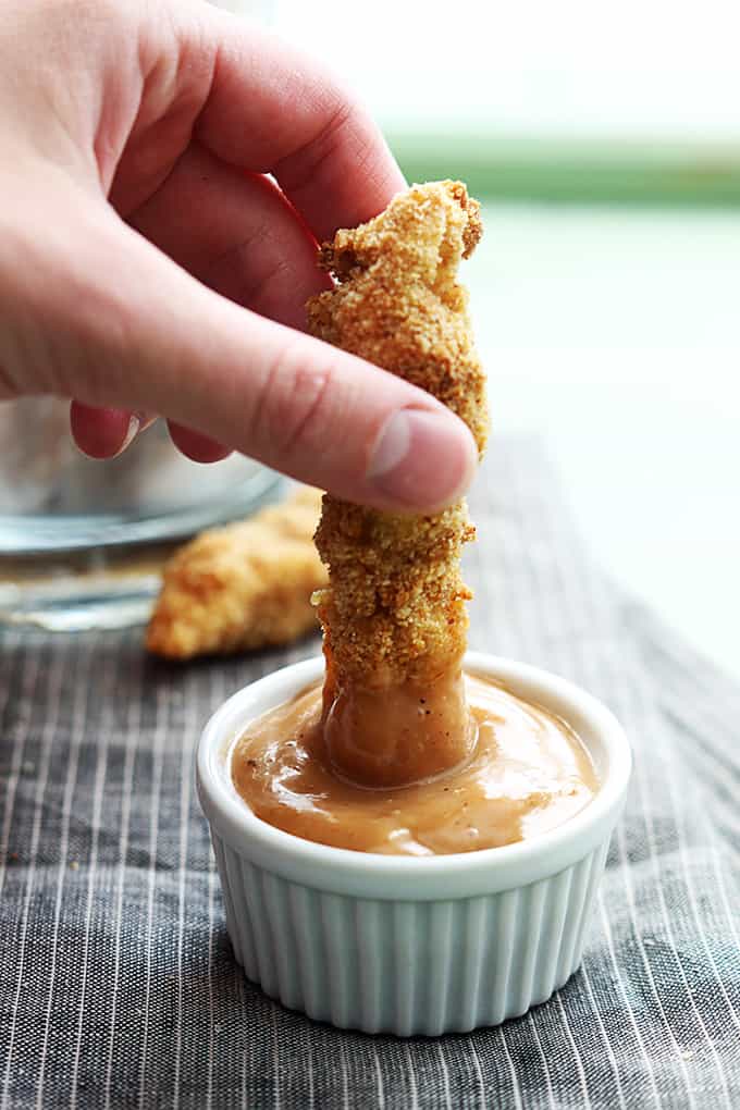 a hand dipping a chicken fry in fry sauce.