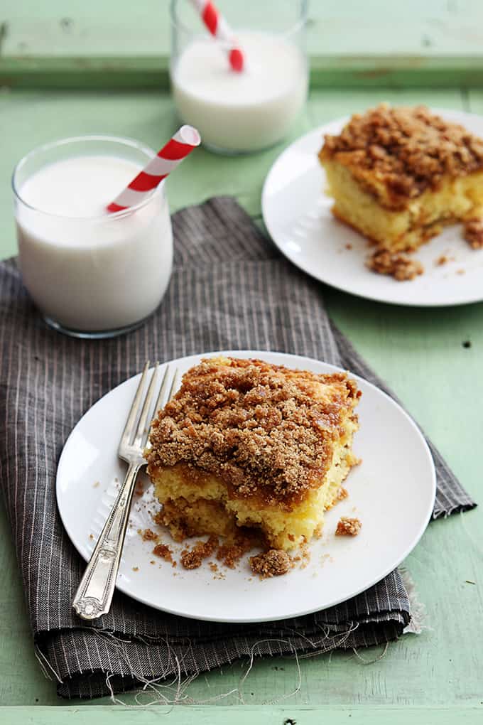 pieces of cake mix sour cream coffee cake on small plates with glasses of milk.