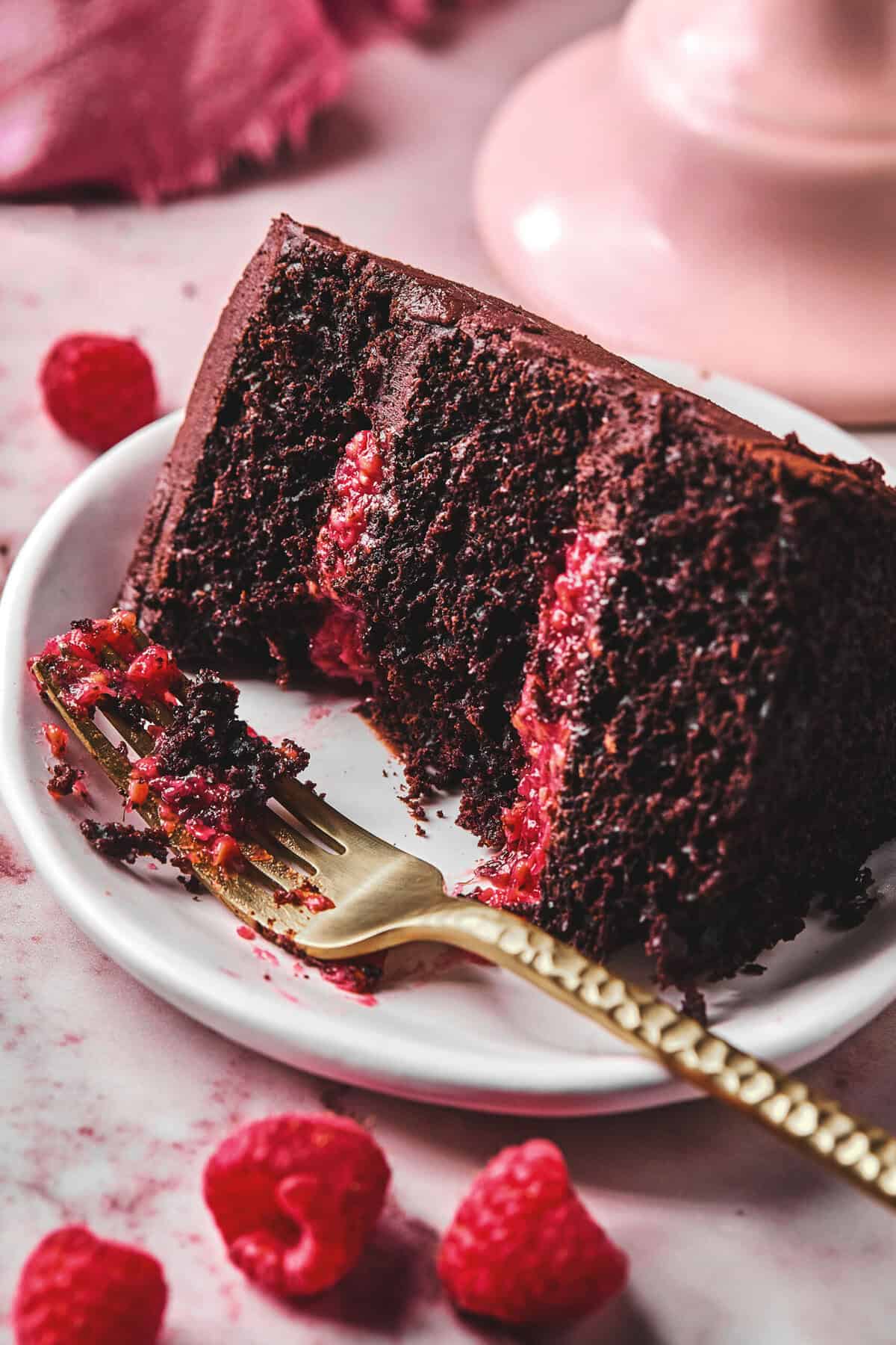 fork and partially eaten chocolate raspberry cake slice on plate.