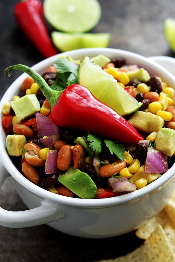 cowboy caviar in a bowl topped with a chili pepper and a slice of a lime.