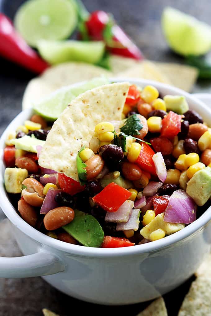 a bowl of cowboy caviar with a chip dipped in it.