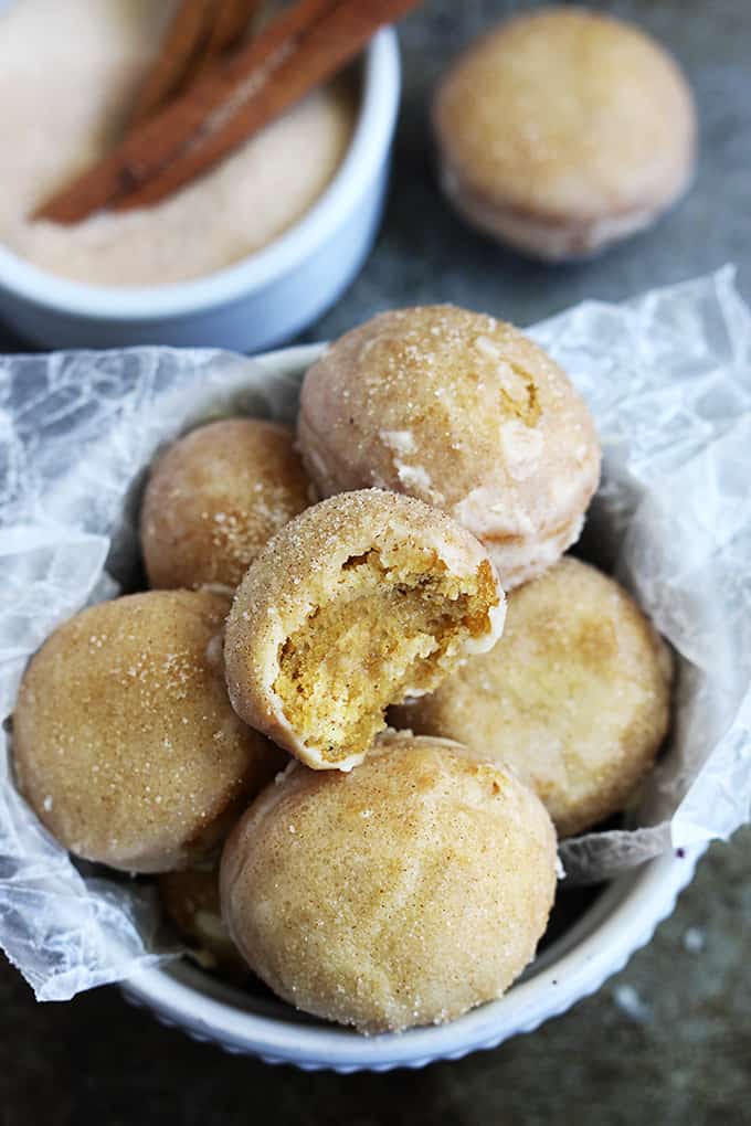 cinnamon sugar glazed pumpkin donut holes with a bite taken from the top one.