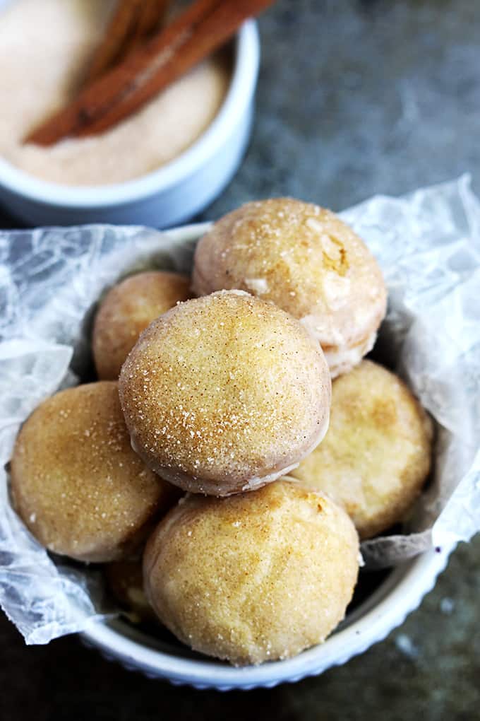 top view of cinnamon sugar glazed pumpkin donut holes in a bowl with cinnamon sugar in the background.