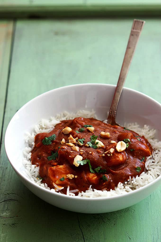 Indian butter chicken on rice with a spoon in a bowl. 