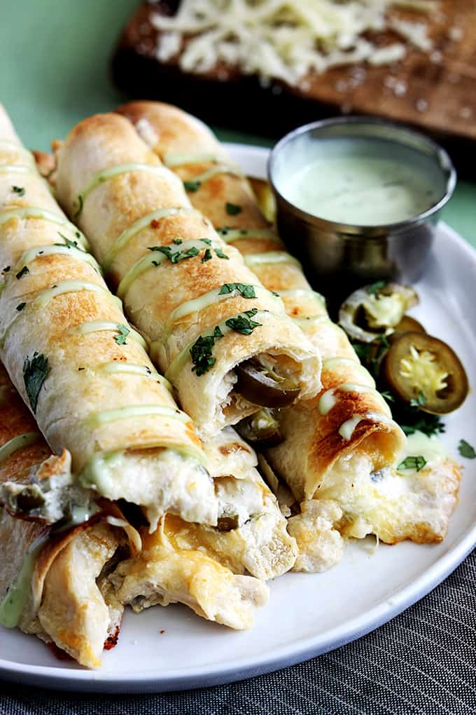 close up of slow cooker jalapeño popper chicken taquitos on a plate with sauce on the side.