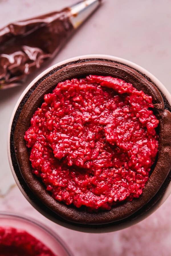 spreading raspberry filling onto chocolate cake