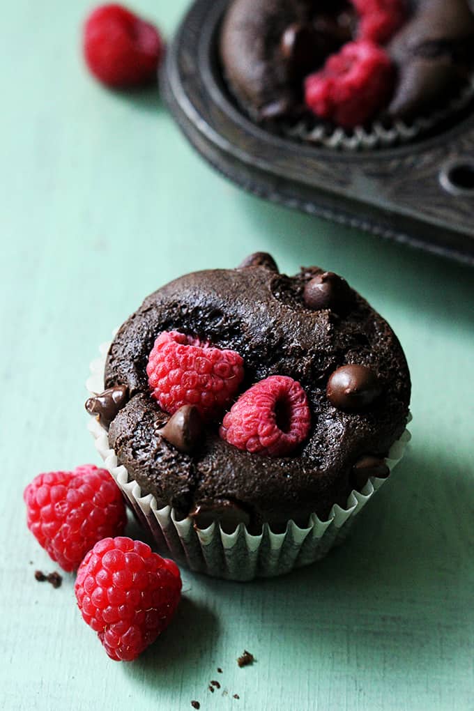 a raspberry chocolate muffin with raspberries on the side.