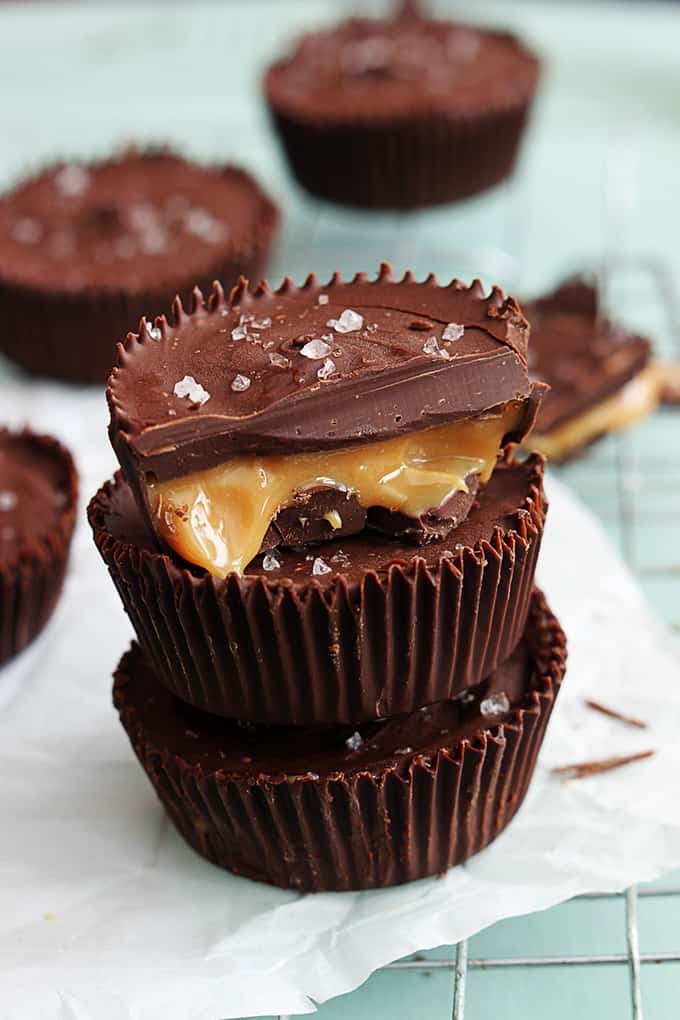 stacked salted caramel cups with half of a caramel cup on top and more faded in the background all on a cooling rack.