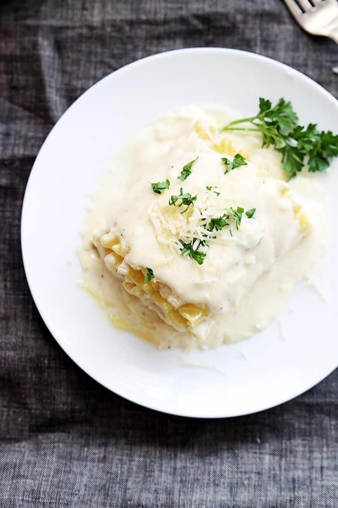 top view of a white chicken lasagna rollup on a plate with a fork on the side.