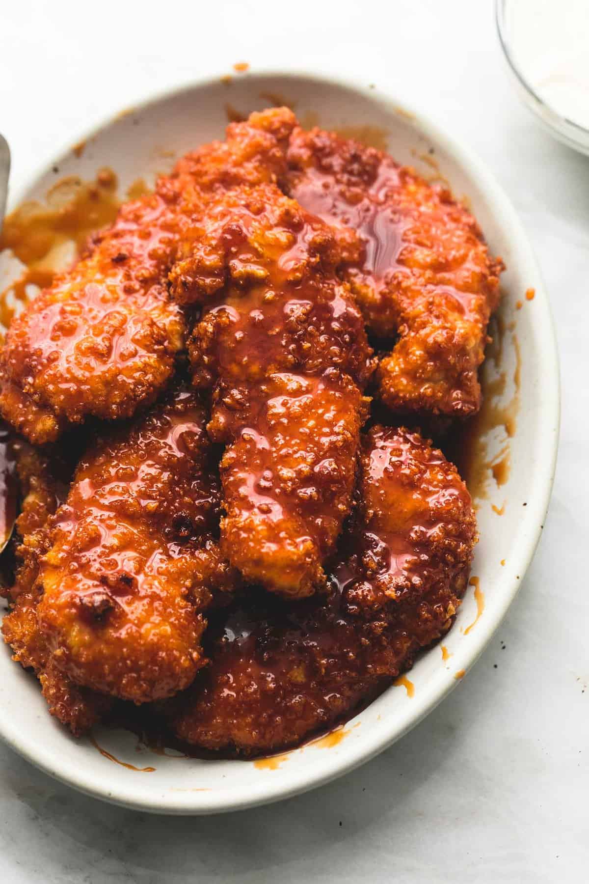 Now you can make famous Winger's sticky fingers right at home anytime you get a craving. Three easy steps will put these saucy baked chicken strips on the table in just 30 minutes! | lecremedelacrumb.com copycat Winger's sticky fingers on a plate.
