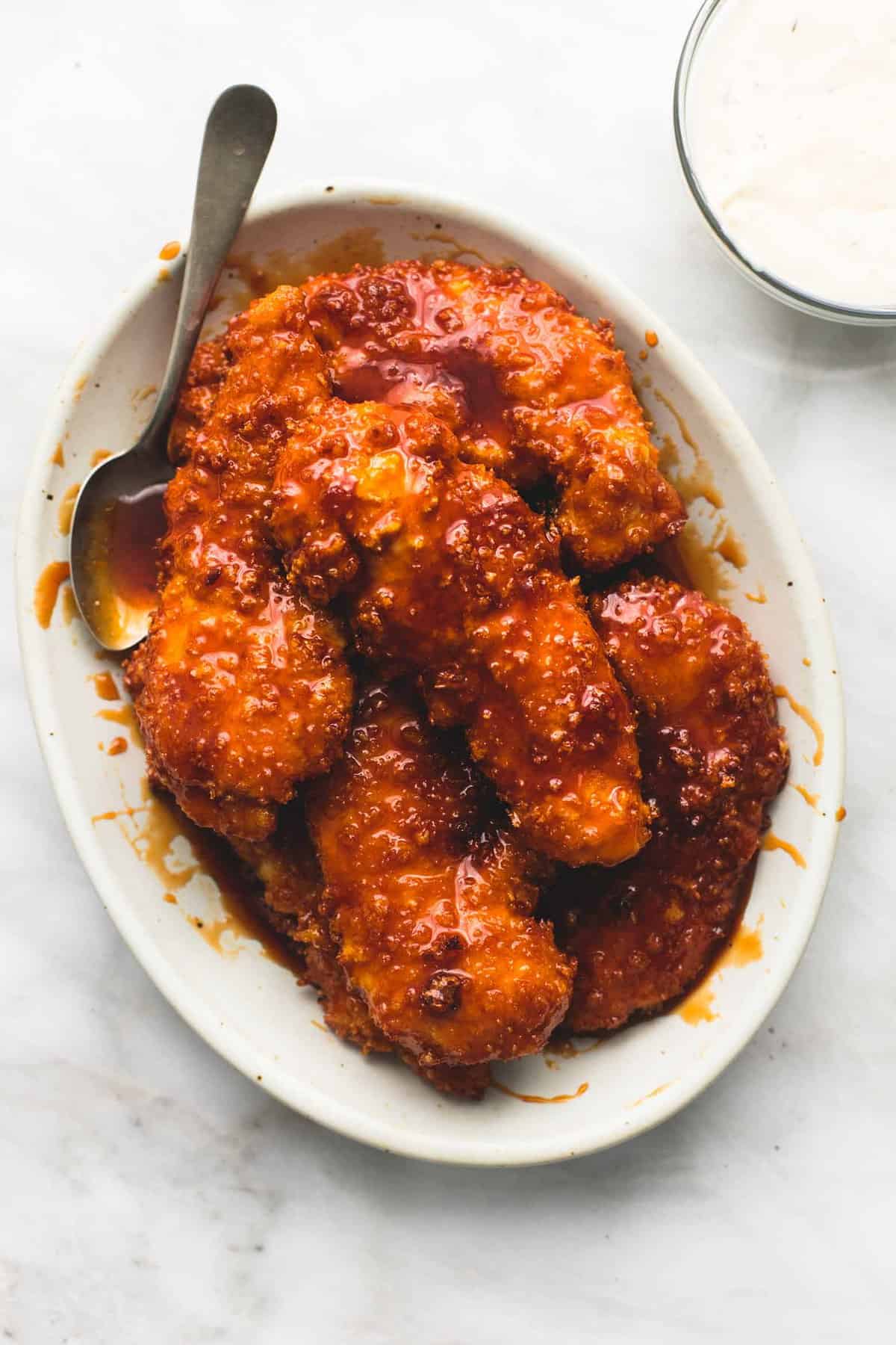 top view of copycat Winger's sticky fingers with a fork on a plate with a bowl of dipping sauce on the side.