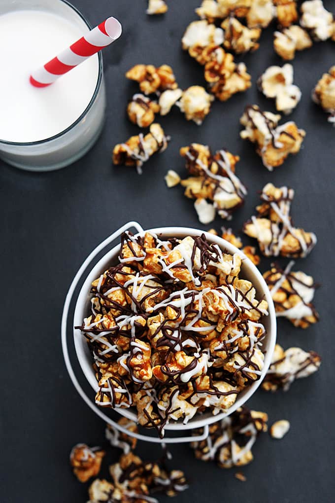 top view of zebra caramel corn in a tin bucket with more popcorn and a glass of milk on the side.