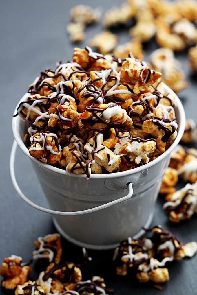 zebra caramel corn in a tin bucket with more popcorn around it.