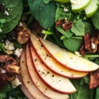 close up view of spinach, arugula, sliced apples, and nuts