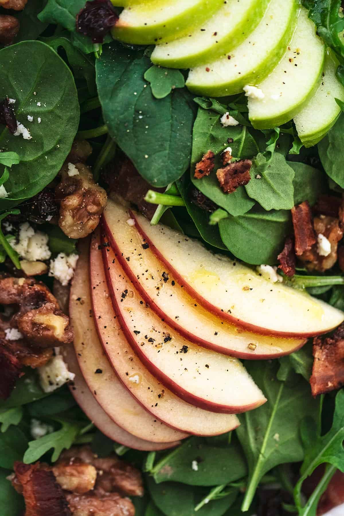 close up view of spinach, arugula, sliced apples, and nuts