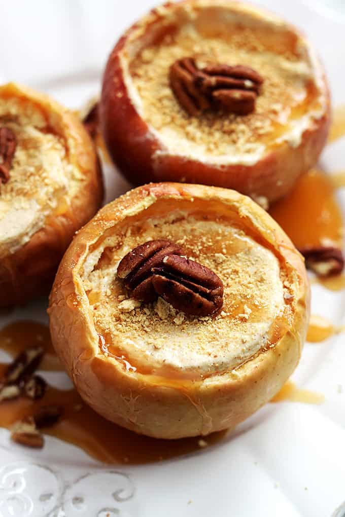 top view of cheesecake stuffed baked apples surrounded by caramel and pecans.