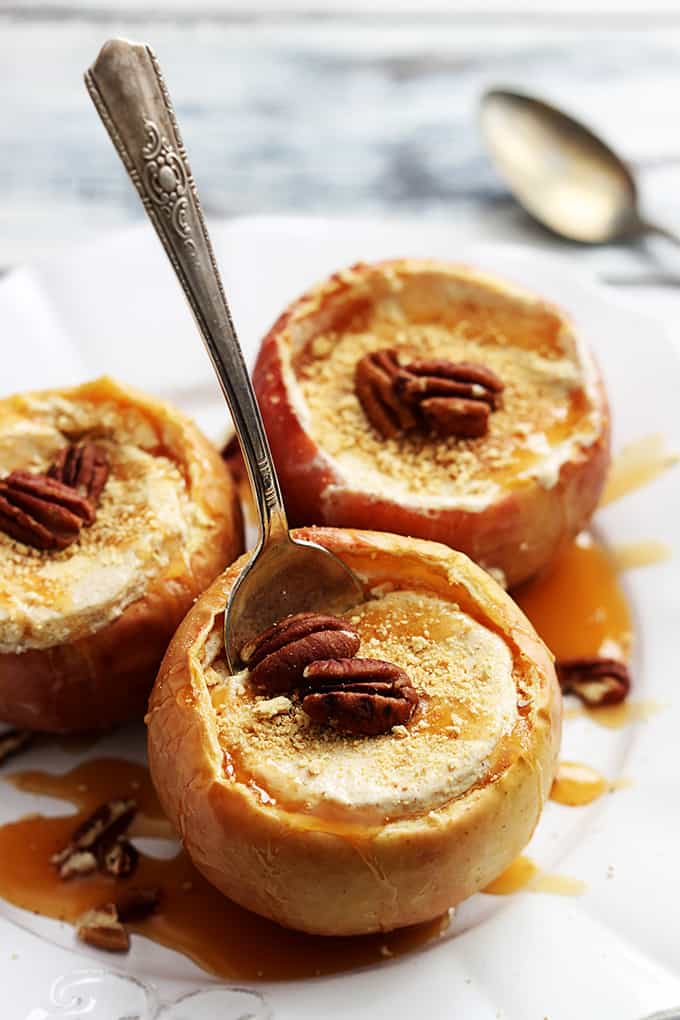 top view of cheesecake stuffed baked apples on a plate with a spoon in the first apple.