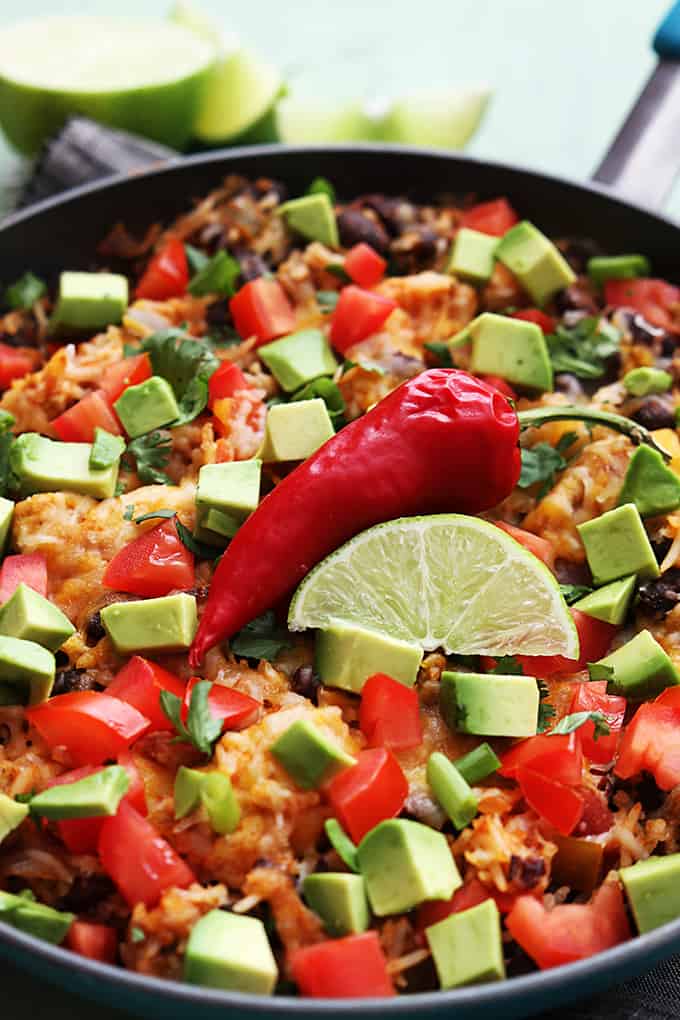 chicken taco rice skillet topped with a red chili pepper and a slice of a lime in a skillet.