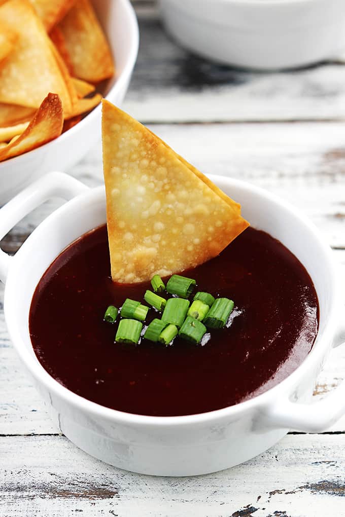 a bowl of cream cheese wonton dip with a wonton on top and a bowl of wontons on the side.