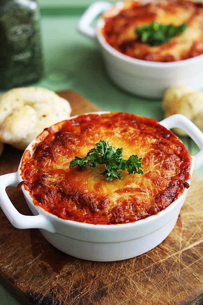 lasagna dip in a serving bowl with breaded knots and more dip faded in the background.