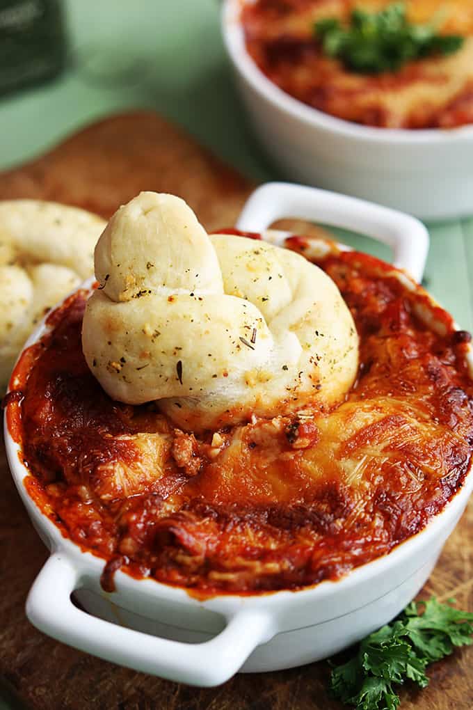 close up of a breaded knot dipped in a serving bowl of lasagna dip.