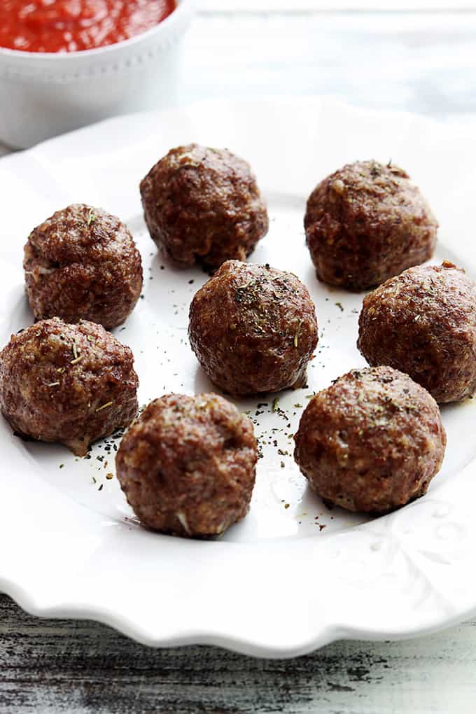 slow cooker mozzarella stuffed meatballs on a plate with marinara in a bowl on the side.