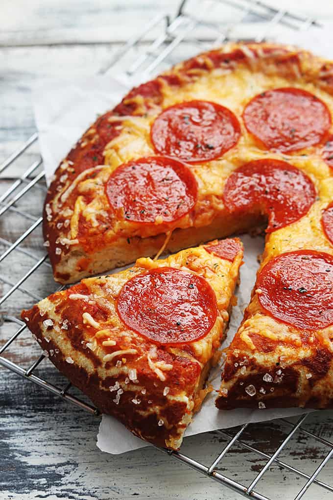 a slice of pretzel crust pizza with the rest of the pizza on the side all on a cooling rack.