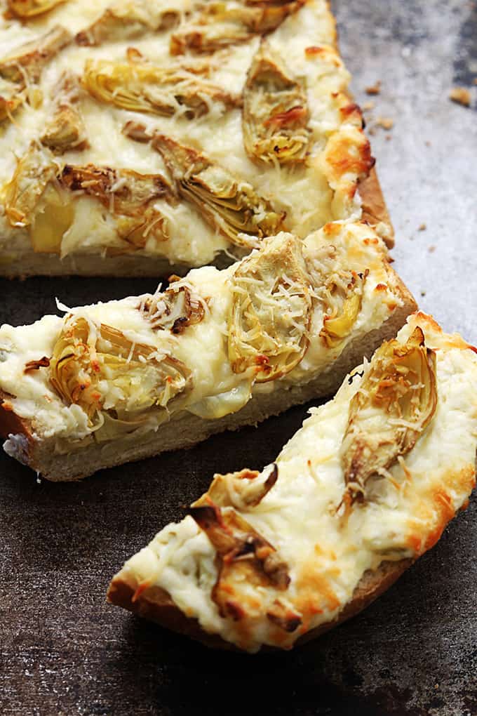 close up of roasted garlic artichoke bread with the front of the bread sliced.