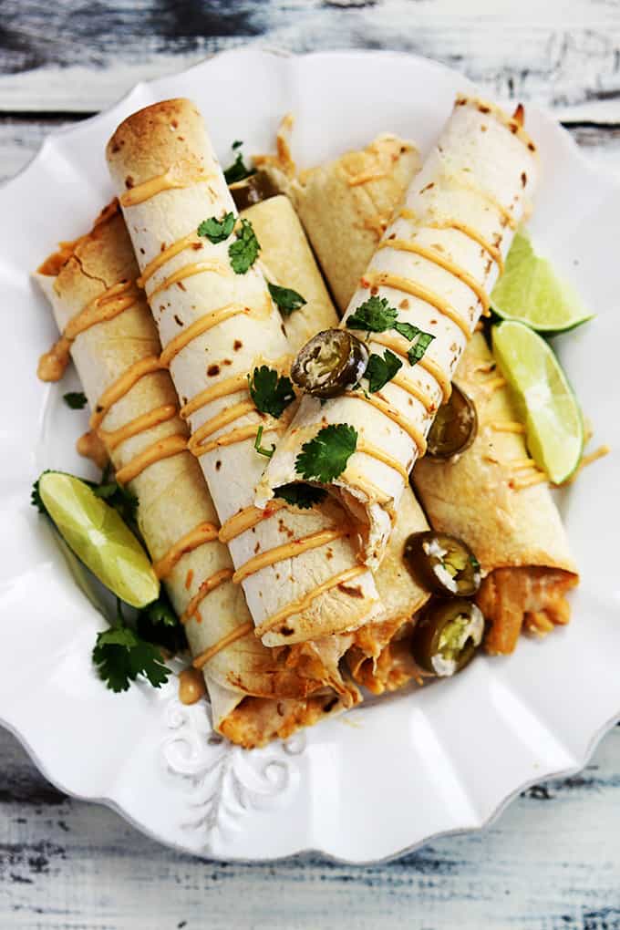 top view of slow cooker creamy chipotle chicken taquitos on a plate with a bite missing from the top taquito.