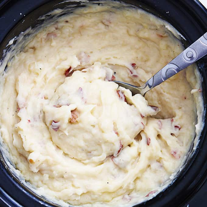 top view of slow cooker mashed potatoes with a serving spoon in a slow cooker.