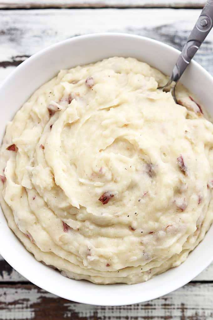 top view of slow cooker mashed potatoes with a spoon in a bowl.
