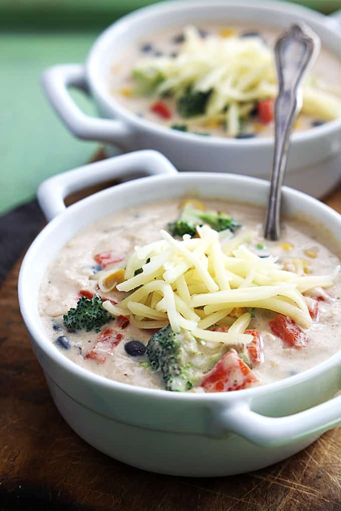 a bowl of southwest broccoli chowder with a spoon and another bowl of chowder faded in the background.