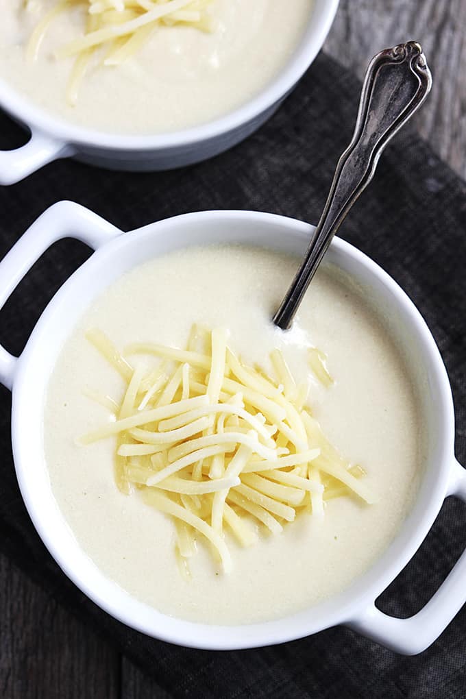 top view of a bowl of Zupas Wisconsin cauliflower soup with a spoon with another bowl on the side.