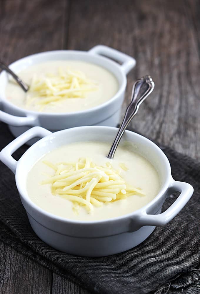 two bowls with spoons of Zupas Wisconsin cauliflower soup on a cloth napkin.