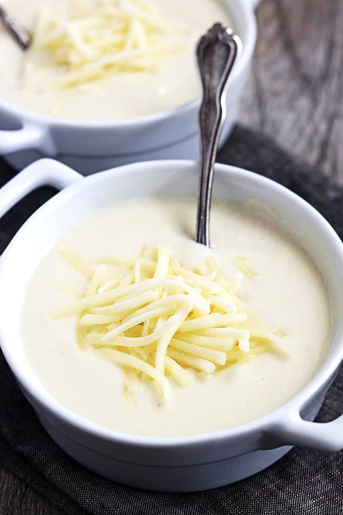 Zupas Wisconsin cauliflower soup with a spoon in a bowl with another bowl faded in the background.