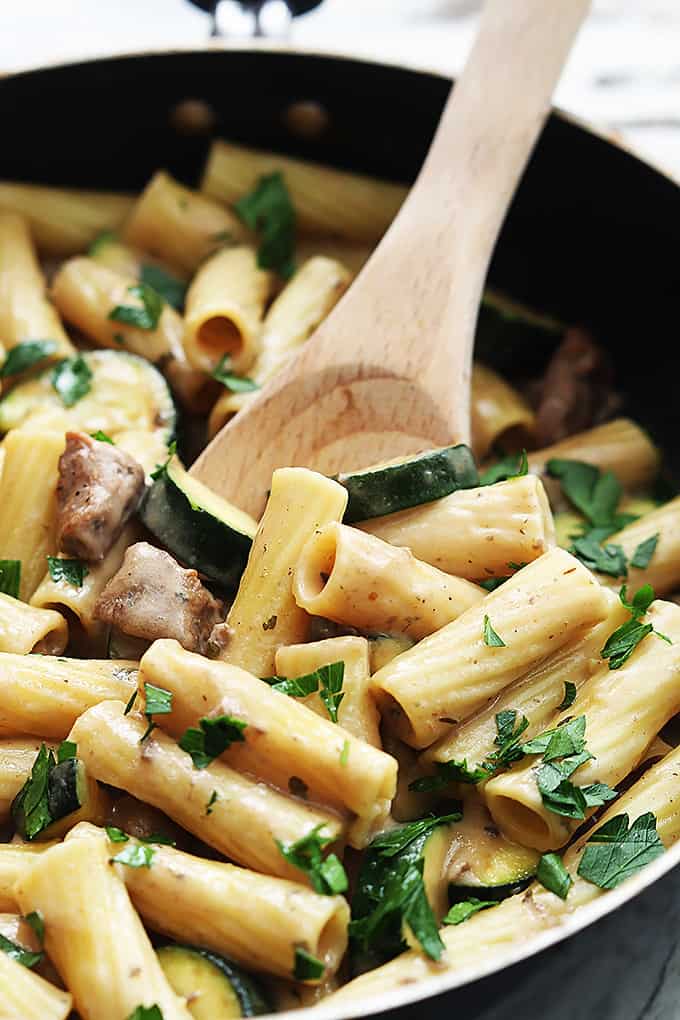close up of speedy sausage rigatoni with a wooden serving spoon in a skillet.