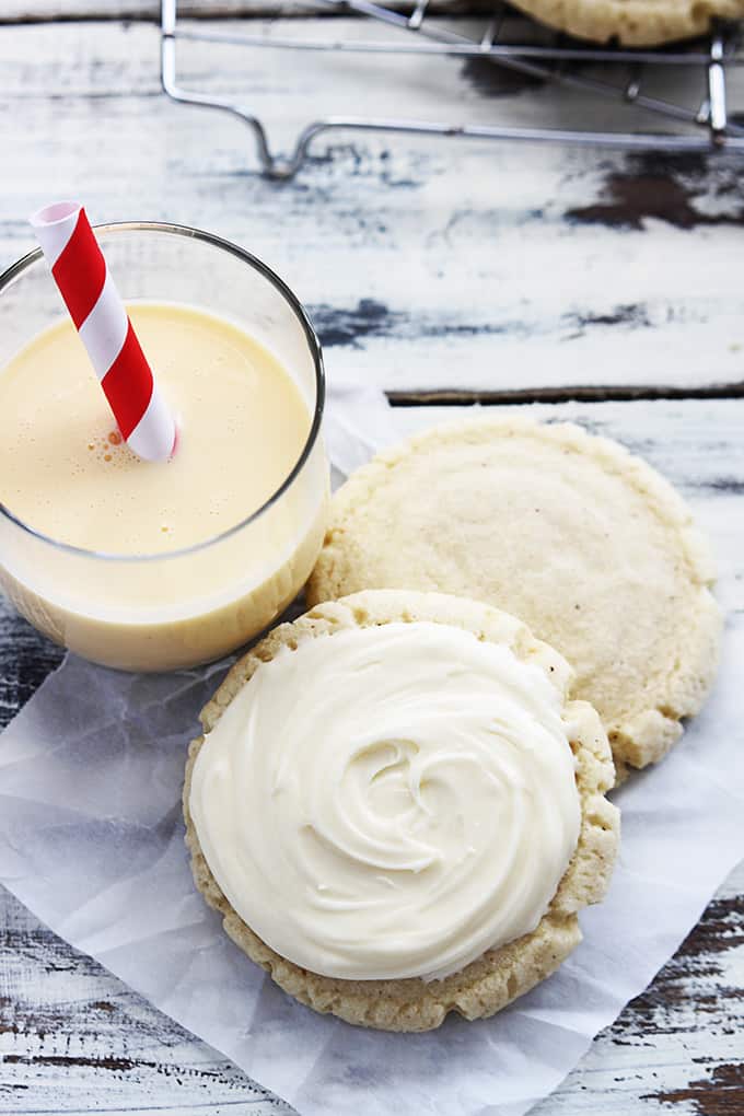 top view of eggnog sugar cookies on a napkin next to a glass of eggnog.