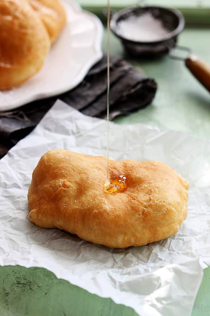 a fried scone with honey being poured on top.